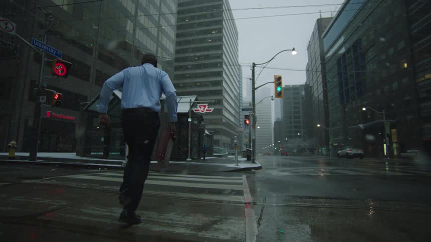 A man carrying a briefcase is running down a city street in the rain