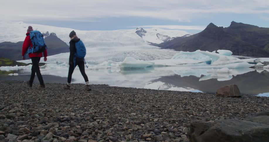 People hike along rocks in an icy area