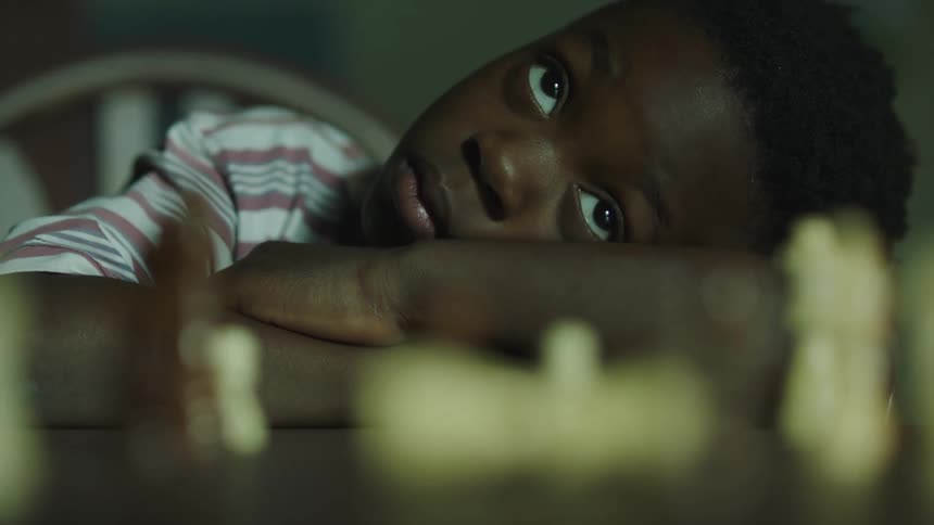 A chess piece falling over on a table in front of a child