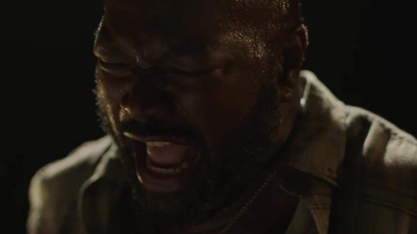 Screaming man playing the drums inside a dark room