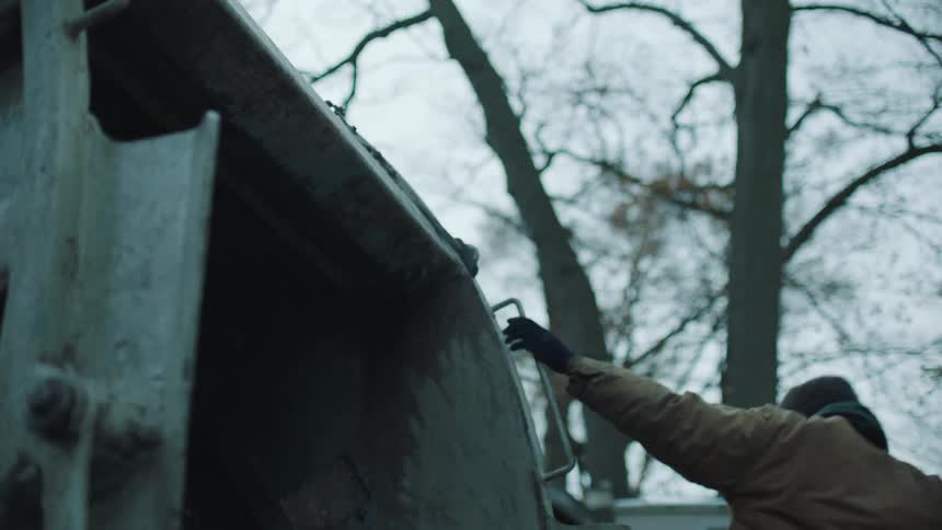Man throws garbage bag into back of garbage truck