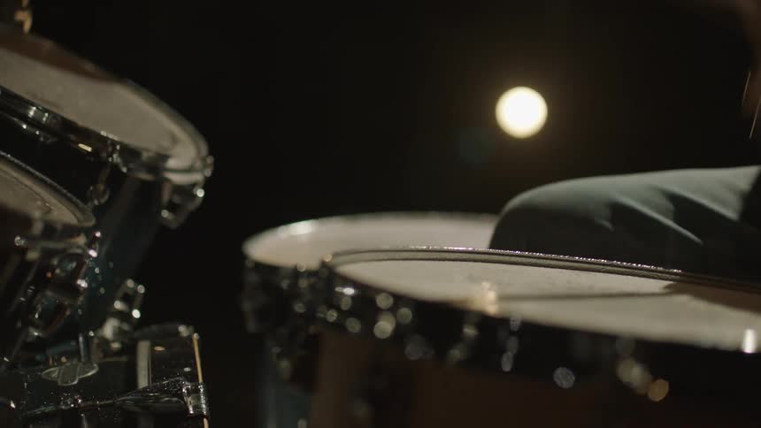 Silhouette of a drummer playing on a drum set on a dark stage