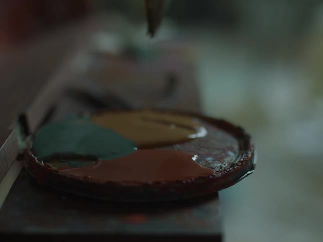Person putting paint on brush