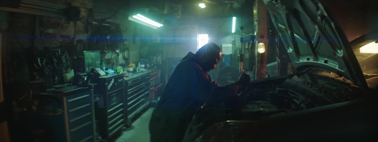 Frustrated mechanic tries to loosen a bolt on the engine of a car inside an autoshop