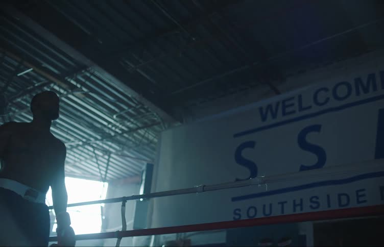 Male boxer with beard boxing trunk and gloves stands in the corner of boxing ring