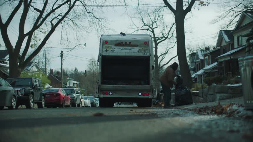 A garbage truck is picking up garbage in a neighborhood