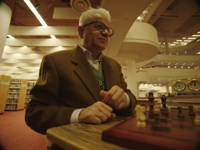 Two men are playing a game of chess in a library