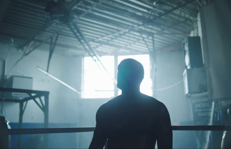 A boxer is standing in the ring with his gloves