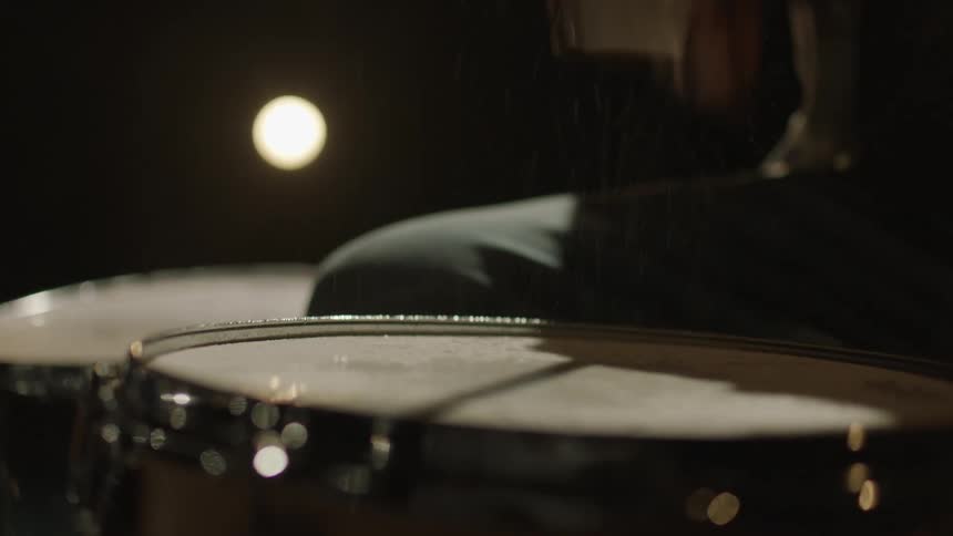 A man plays the drums outside in the rain