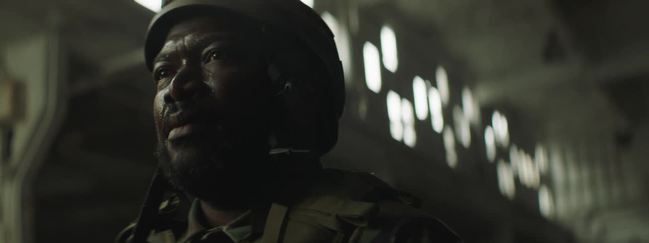 A soldier stands inside a building and looks ahead