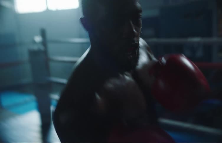 A male boxer punches and jabs quickly in a boxing ring by himself
