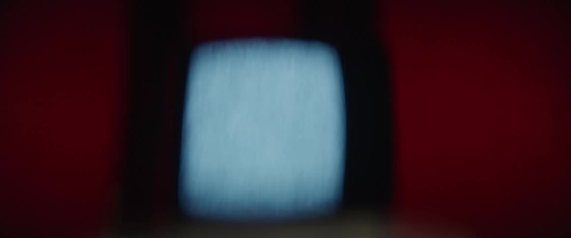 A television with static on the screen is pulsating as a strobe light flashes