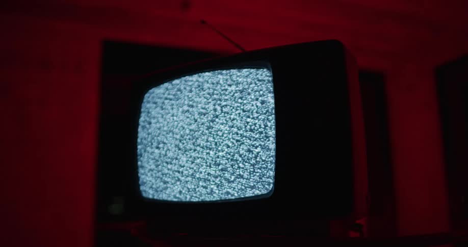Television with fuzzy screen on table in front of red background