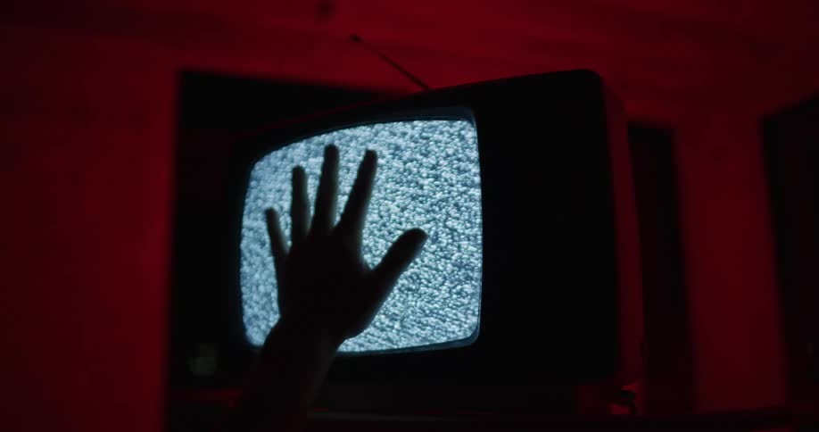 A person is reaching and touching a retro television
