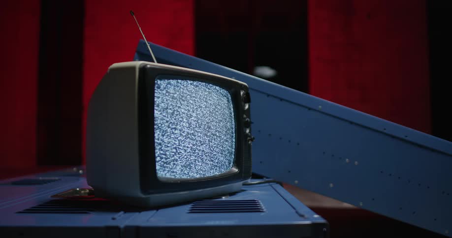 A portable television is sitting on a table and static is on the screen