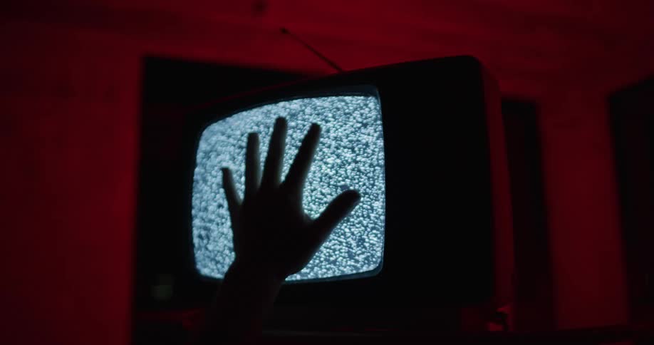 A persons hand is on a retro television