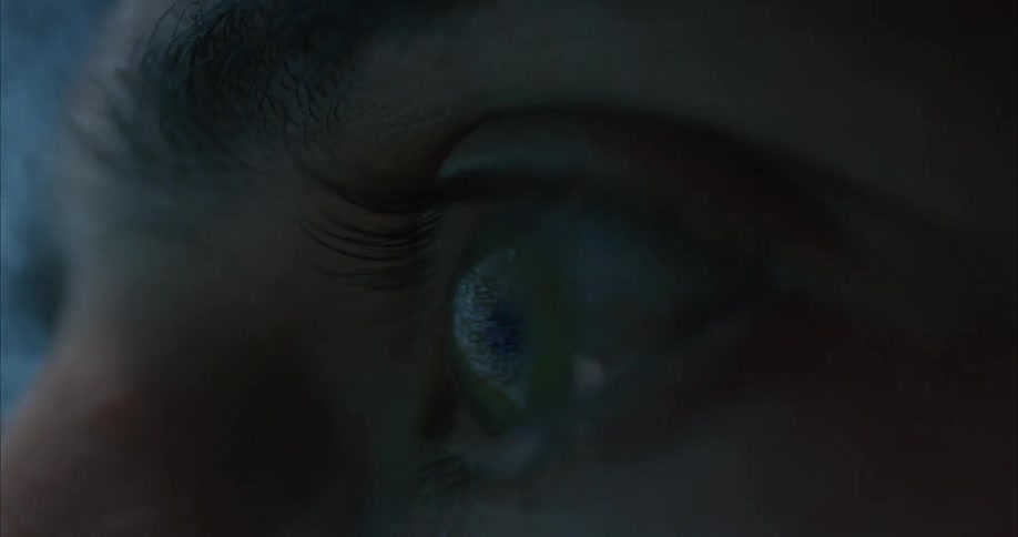 A man presses his eye against a television screen as static plays