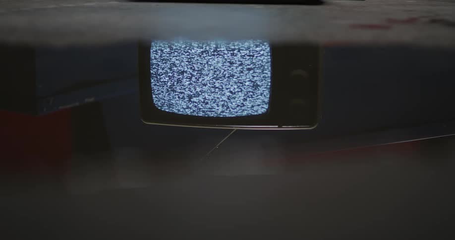 Vintage television inside a dimly lit room show static on the screen