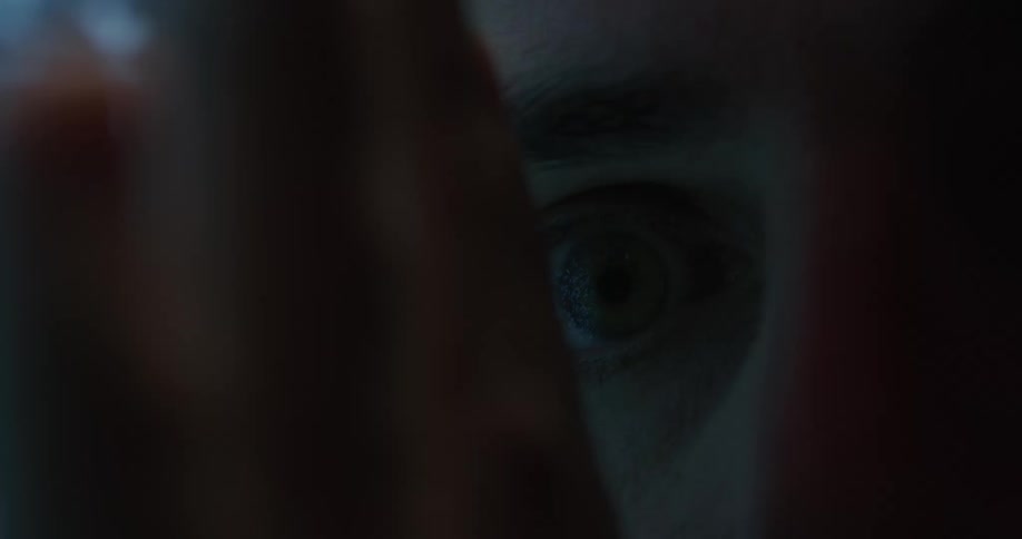 Close up of the eye of a young man caressing the screen of a television showing static