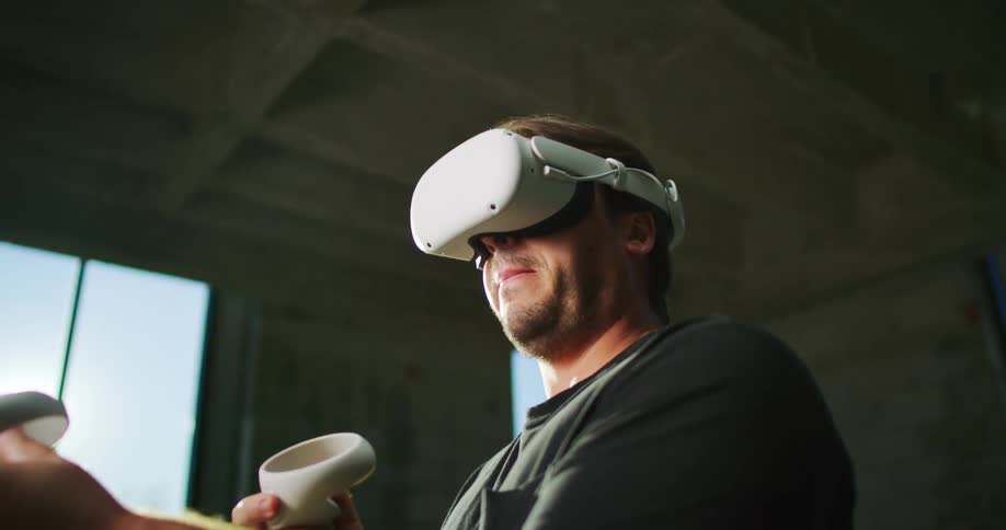 A man plays a game using a virtual reality headset indoors during the day