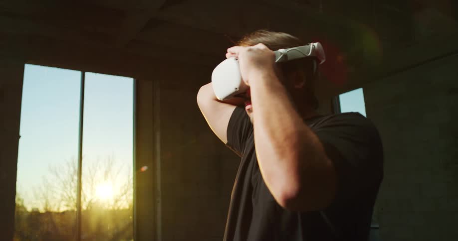 A man is standing in a room and putting on a headset for a virtual reality game