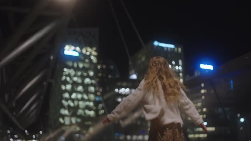 A woman is running through a downtown city at night