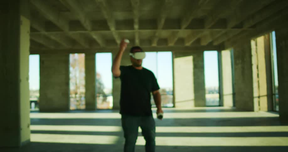 A man wearing a virtual reality headset is holding game controllers as he plays a game