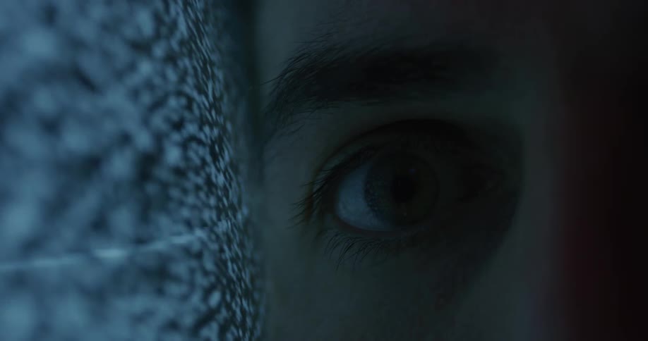 A man sits with his cheek pressed against the side of a television showing black and white static