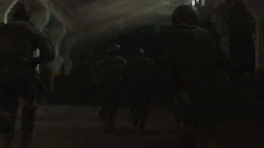 Soldiers run through the dark warehouse