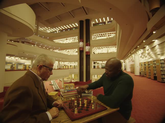 Two men paying chess in a room