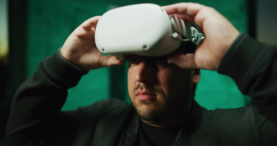 Man standing inside a room puts on white virtual reality goggles