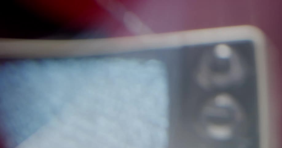 An old model television with dials and antenna plays static