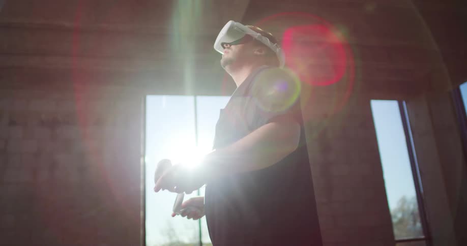 Man using a virtual reality set inside a room in front of a window
