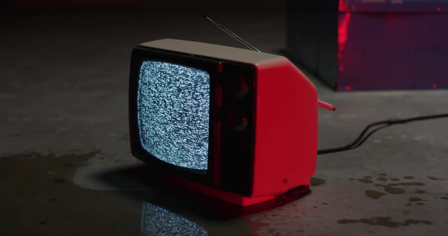 Vintage television over the wet concrete floor of a room showing static on the screen