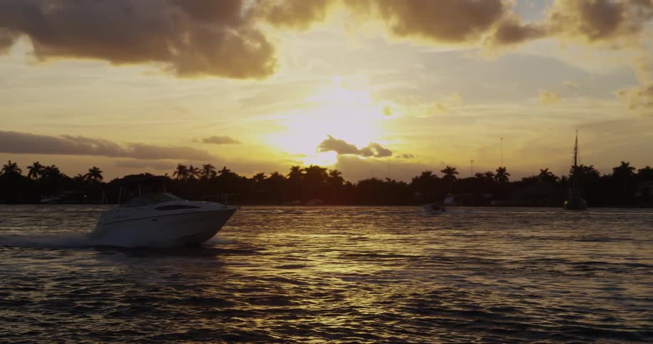 A boat moves fast across the water at sunset
