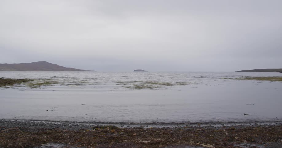 Waves slowly hit the shore on a cloudy day