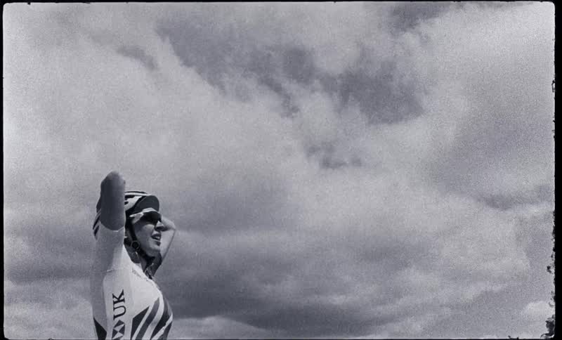 Black and white footage of a woman wearing cyclism gear resting caught on vintage film