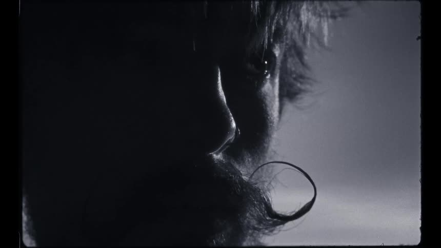 A man stands with the ends of his mustache twisted and curved up