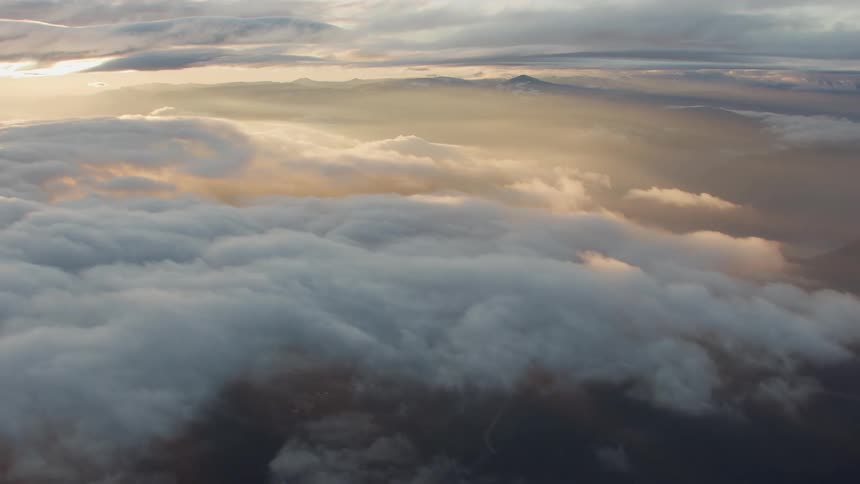 Sunset magic revealed as one flies through stunning clouds high above a national forest