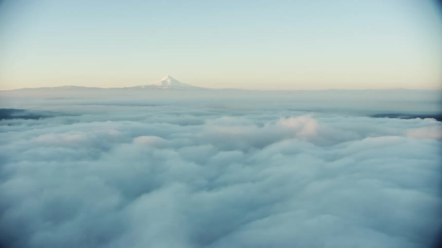 Morning fog covers the river valley on a crisp winter morning with a huge snow covered mountain in the background