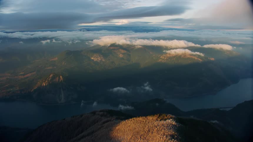 Stunning perspective above a massive river valley with sunlit clouds sitting on top of a pristine forest