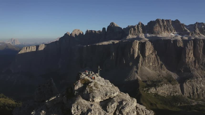 People stand on a mountain next to a large cross