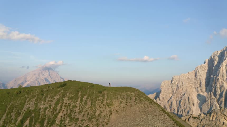 A man hikes along a ridge in a mountain range