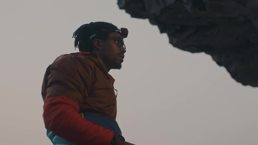 A mountain climber near a cliff fixes his rope