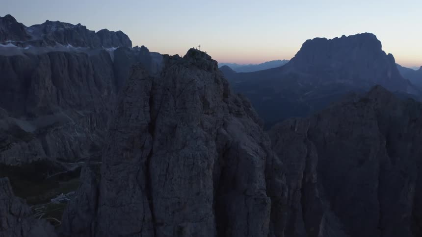 An aerial view of a mountain range with some crosses on a peak