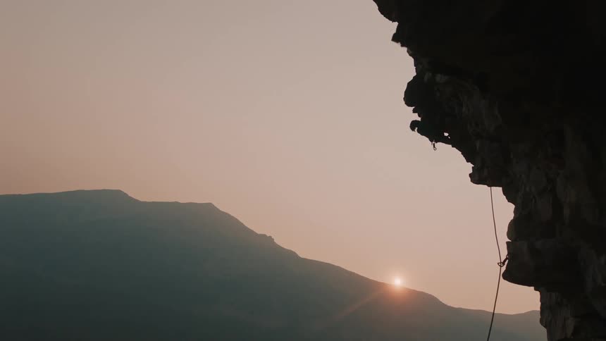 A rock climbing pulls himself up on the side of the mountain