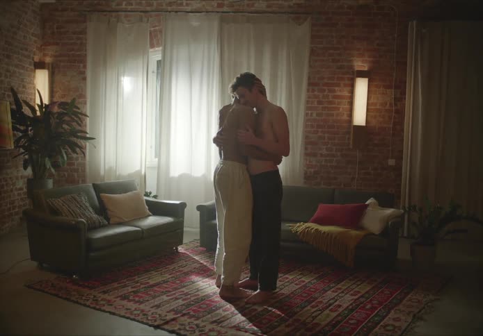 Young shirtless couple hug and dance on the living room at home