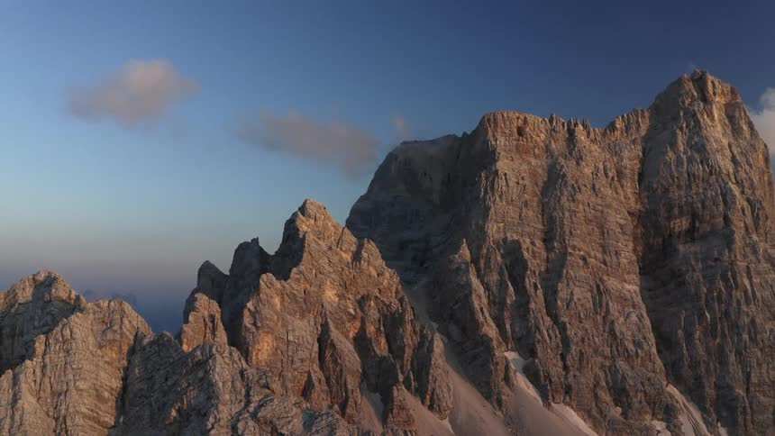Aerial view of the cliffs on the slopes of a tall mountain range in the morning