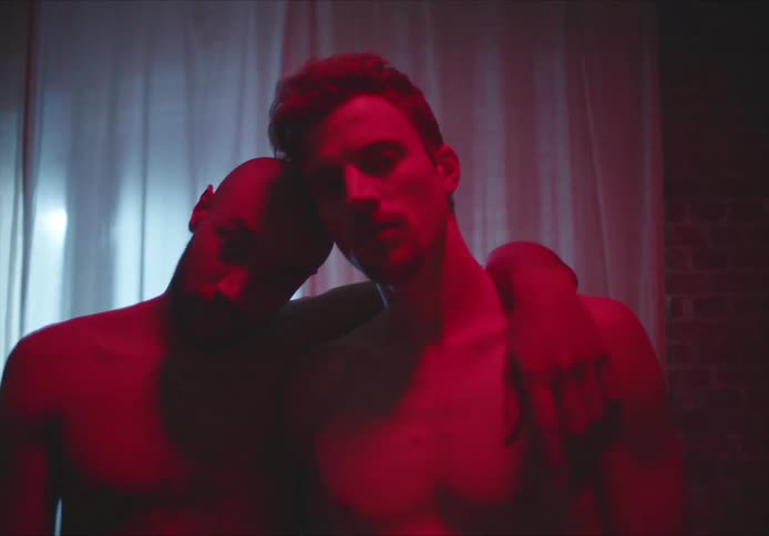 A couple stand together under the red lighting