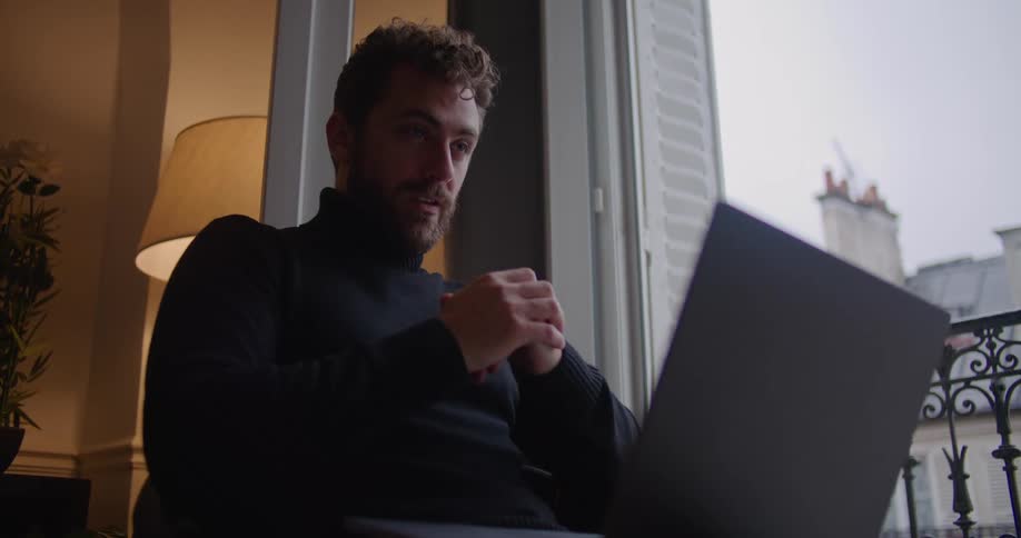 A man is talking to someone on his laptop